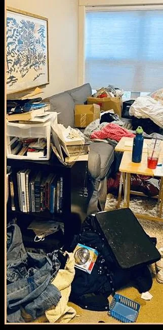 Before: the same living room moderately messy and cluttered, with boxes, laundry, books, and household items piled around the same gray sectional sofa